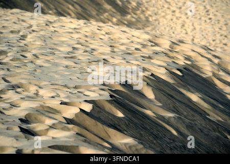 Close-up aerial perspective of wind-sculpted sand ripples casting dramatic shadows across a coastal dune in Skagen, Denmark. Stock Photo