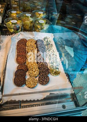 Assorted Chocolate Discs with Nuts, Cocoa Nibs and Pistachios Displayed at CUITO Caffè Cioccolato in Rome Fiumicino Airport, Italy Stock Photo