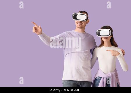 Virtual reality experience and metaverse technology, happy couple wearing vr headsets exploring digital world and interactive gaming on purple backgro Stock Photo