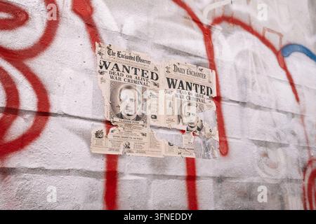 25.09.26, Close view of wanted posters and graffiti , Berlin, Germany A close view shows two torn, newspaper-style posters carrying the words WANTED and WAR CRIMINAL on a red graffiti-covered wall. One bears the portrait and name of Vladimir Putin. Berlin Berlin Berlin Germany Stock Photo