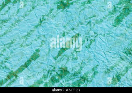 Turquoise crumpled paper texture with irregular green streaks forming an abstract background Stock Photo