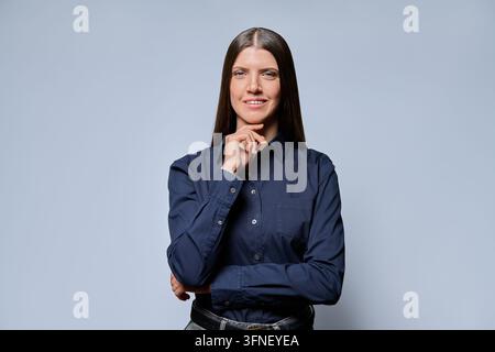 Smiling businesswoman touching chin and looking at camera in studio shot Stock Photo