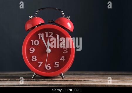 Close up red vintage alarm clock pointing to twelve on dark background Stock Photo
