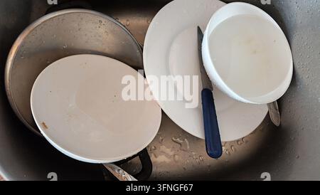 Dirty unwashed dishes in a stainless steel kitchen sink Stock Photo