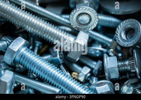 Many shiny metal bolts, nuts, and screws mixed together for a hardware background Stock Photo