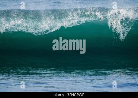 Powerful turquoise ocean barrel wave breaking in clear blue water with dramatic white spray Stock Photo
