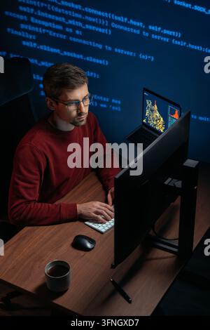 Coder or data scientist in glasses working at dark workspace with multiple monitors. Software engineer types script on keyboard, working on AI development project. Copy space.  Stock Photo
