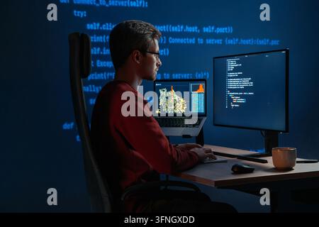 Data scientist writing code for artificial intelligence project, with programming scripts visible across desktop monitors. Coder in glasses working in front multiple screens at night. Copy space Stock Photo