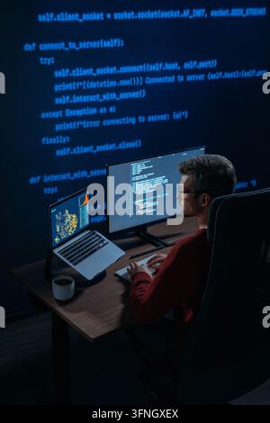 Software engineer sits at a desk with multiple monitors showing script and data science graphs in a dark room with programming code on background, works on AI and machine learning project. Copy space Stock Photo