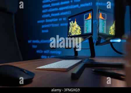 Close up of dark programming workspace featuring laptop, desktop monitor, keyboard and mouse. Modern software development environment. Space for text Stock Photo