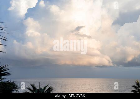 Dramatic soft golden sky with storm clouds gathering over the calm ocean surface at sunset Stock Photo