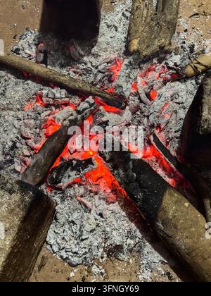 smoldering campfire logs with glowing red embers and grey ash, outdoor survival and camping background concept in top view Stock Photo