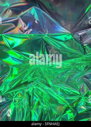 Bright green and silver iridescent foil, crumpled and textured. Reflective surface catches light, creating prismatic effects. Abstract background suit Stock Photo