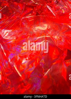 Vibrant red wrinkled plastic sheeting creates abstract textured background. Sharp highlights and diffused shadows add depth. Ideal for design elements Stock Photo