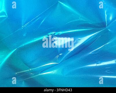 Abstract background bright blue colored material exhibiting glossy texture and crinkled surface. Suitable for design backgrounds, packaging, or abstra Stock Photo