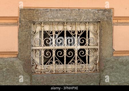 Old closed rusty metal cage window frame on exterior house facade wall Stock Photo
