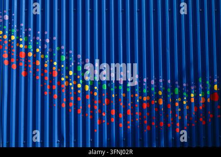 Abstract colorful dots form a flowing wave across a deep blue ridged background, creating a vibrant modern pattern with motion and rhythm. Stock Photo