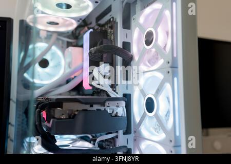 Close-up view of a white gaming computer case with illuminated RGB cooling fans, visible graphics card, cables, and liquid cooling components in a mod Stock Photo