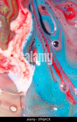 Vibrant abstract fluid art with blue, red, pink, white and metallic paint swirling into marbled patterns, bubbles and glossy organic waves for a color Stock Photo