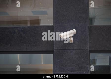 Surveillance camera mounted on a dark wall in a modern building Stock Photo