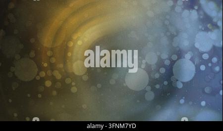 A textured abstract background displaying a blend of blue and gold tones with soft, circular bokeh light effects and a grainy finish. Stock Photo