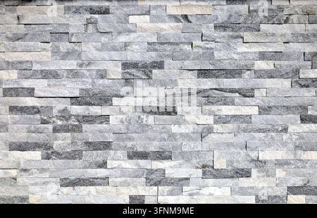 Modern wall covering made of gray, black and white quartzite stone strips. Full frame, background and texture. Stock Photo