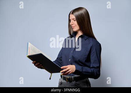 Young focused woman reading notebook in studio portrait Stock Photo