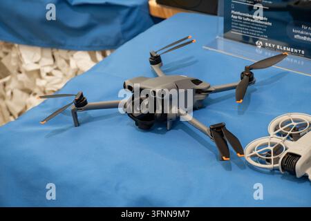 VIENNA, AUSTRIA, 26 October 2026,: A grey foldable camera drone is displayed on a blue table at an exhibition. Stock Photo