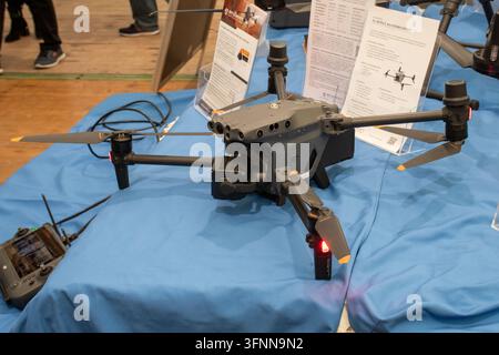 VIENNA, AUSTRIA, 26 October 2026,: A professional quadcopter drone is displayed on a blue table at an exhibition. Stock Photo