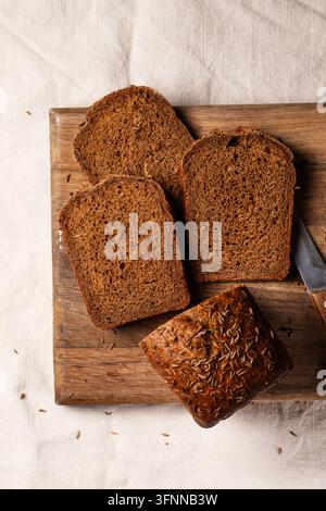 Top view of dark malt bread slices arranged with a seeded loaf on a wooden cutting board, creating a simple rustic composition for wholesome food them Stock Photo