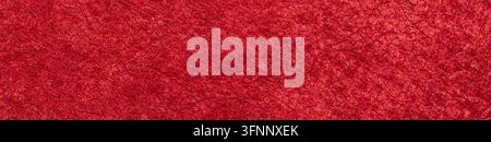 Detailed macro shot of a vibrant crimson suede leather surface featuring a velvety nap texture and soft tactile appearance with warm ambient lighting. Stock Photo