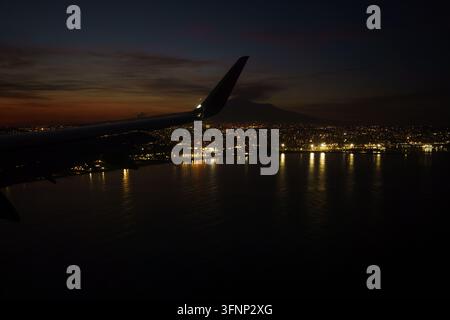 Aerial view from an airplane window at night cityscape Catania, Italy, during landing approach, view of Mount Etna, aerial perspective of urban lights and coastline at night, flight adventure Stock Photo