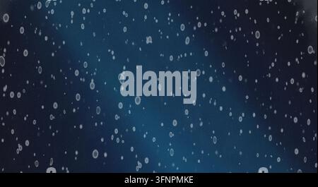 Abstract background featuring glowing particles and dust floating on a dark textured surface with subtle blue gradient lighting. Stock Photo