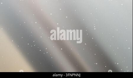 Abstract metallic silver gradient background with subtle wave patterns and glowing speckles creating a shimmering effect. Stock Photo