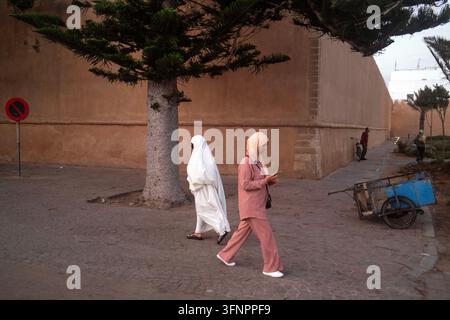 Two women walk a city wall in Essaouira, Morocco Stock Photo