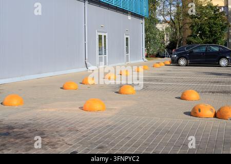Yellow concrete hemisphere barriers on a paved sidewalk. Safety barriers separate the shopping mall parking lot zone along a paved sidewalk near a sho Stock Photo