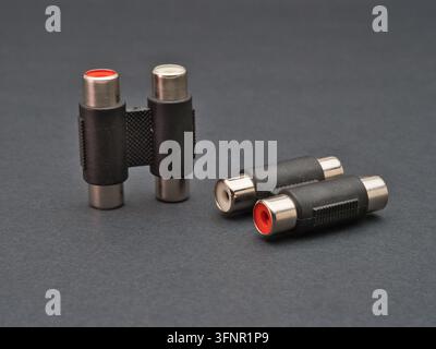 RCA Cable Audio Video Adapters - Two pairs of RCA cable audio and video adapters are placed on a dark gray surface, used for connecting electronic dev Stock Photo
