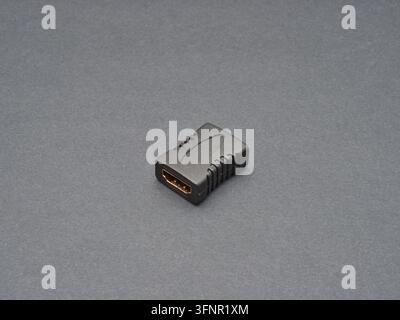 Black HDMI Adapter Connector - A close-up studio shot of a black HDMI adapter or connector with gold-plated contacts on a neutral gray background, hig Stock Photo
