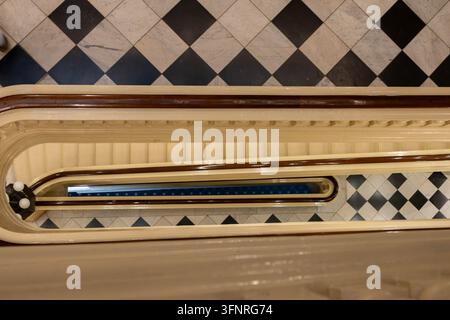 Philadelphia, Pennsylvania - August 29, 2026: High angle abstract view looking down central well of curved wooden balustrade to checkered marble foyer Stock Photo