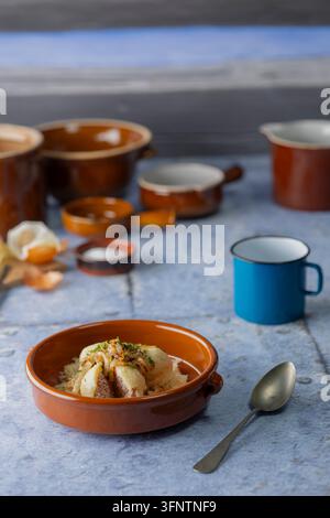 Rustic ceramic bowl presenting potato dumplings filled with meat and topped with caramelized onions Stock Photo