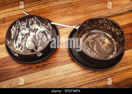 Empty dirty bowls with leftover food residue sitting on a wooden table Stock Photo