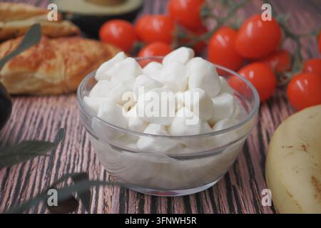 Fresh Mozzarella Balls in Glass Bowl with Cherry Tomatoes and Pastry on Rustic Table Stock Photo