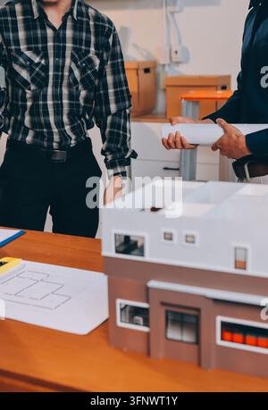 Asian architect and engineer team checking architectural house model using measuring tape on the table at office studio. Stock Photo