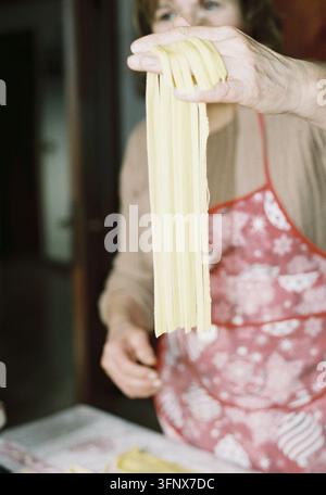 analog photo of close up old italian grandma holding fresh handmade pasta at home Stock Photo