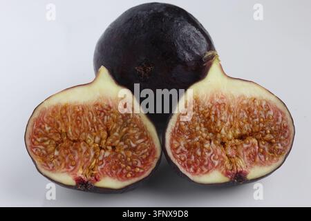 Fresh Ripe Black Fig Whole and Sliced Halves Displaying Juicy Pulp Isolated on Smooth White Background Stock Photo