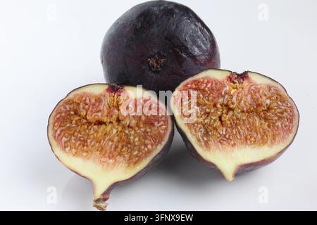 Fresh Ripe Black Fig Whole and Sliced Halves Displaying Juicy Pulp Isolated on Smooth White Background Stock Photo