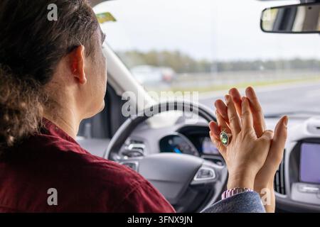 Close-up of a man and a woman pressing palms and holding hands while driving on a highway. Emotional concept of love, trust, togetherness, and partner Stock Photo