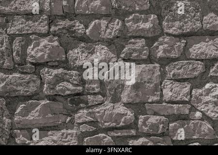 Detailed background texture of old grey stone wall built from rough natural limestone blocks for architectural, historical, or outdoor mockup. Stock Photo