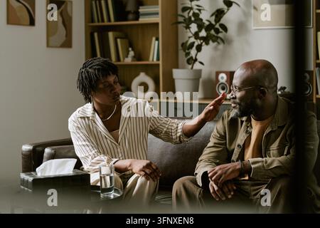 Black Woman Psychologist Supporting Middle Aged Black Man in Therapy Stock Photo