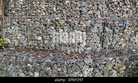 Gabion wall filled with natural stones enclosed in metal wire mesh Stock Photo